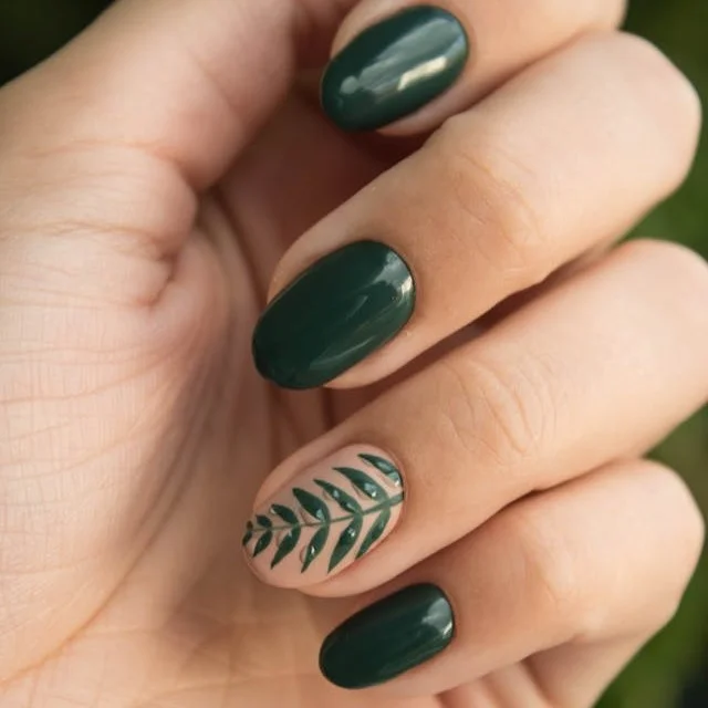 Rounded finger nails, painted green with a matte leaf design on the ring finger